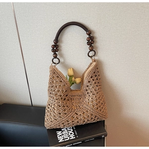 Detail of woven straw tote bag featuring vintage wooden beads and hollow crochet pattern