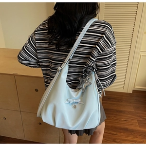 Close-up of light blue hobo bag with a silver star charm and metallic heart detail
