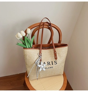 Close-up of rainbow straw tote bag with brown leather handles and star tassel charm