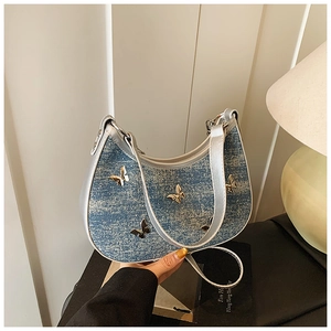 Dettaglio borsa hobo in denim con farfalle dorate 3D e bordi in pelle argentata