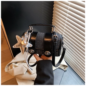 Détail du sac à main en denim à pois gris avec double fermoirs et pendentif en étoile