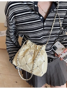 Sac seau matelassé crème avec strass en étoile et bandoulière chaîne sur le mannequin