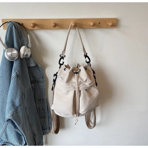 Detailed cream bucket bag hanging on a hook with high-density texture and drawstrings