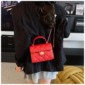 Close-up of red quilted crossbody bag with gold turn-lock and woven chain strap on model
