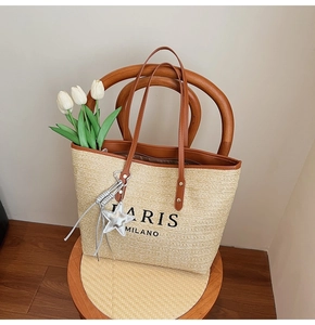 Detailed close-up of rainbow woven tote bag with leather handles and silver star charm