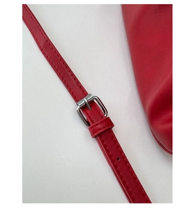 Detail of red leather shoulder strap with silver adjustable buckle and fine stitching