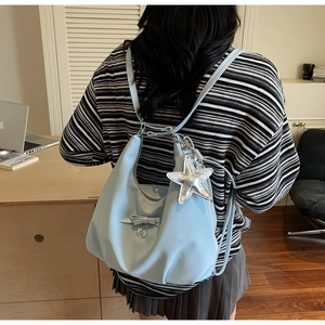 Detail of light blue hobo bag with star and heart charms worn by model in office setting