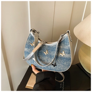 Dettaglio borsa a luna in denim vintage con farfalle metalliche e tracolla in pelle PU
