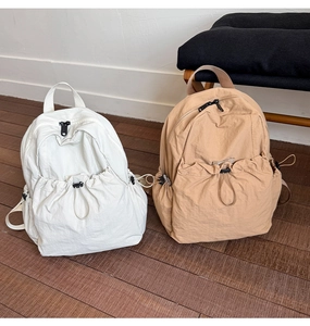 Detail of nylon drawstring backpacks in beige and khaki with functional side toggles