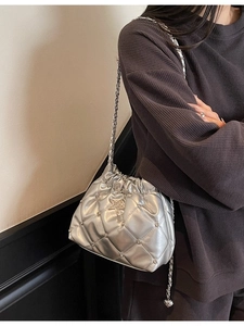 Sac seau matelassé argenté avec badge étoile et chaîne métallique sur modèle