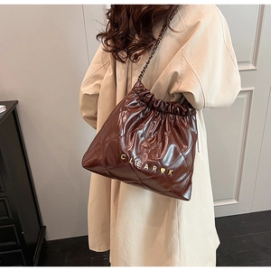 Detailed view of brown quilted faux leather tote with chain strap and drawstring closure