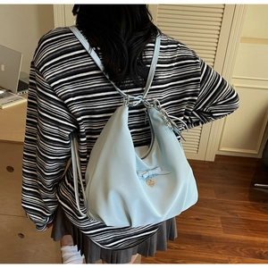 Detail of light blue nylon convertible bag with ribbon bows and heart pendant detail