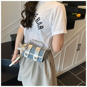 Détail du sac bandoulière en denim bleu avec bordure argentée et breloque étoile de mer