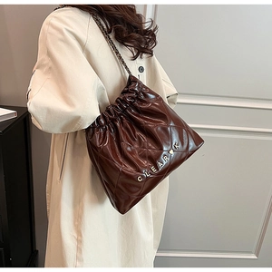 Close-up of quilted dark brown leather bucket bag with metallic Clear K logo and chain strap