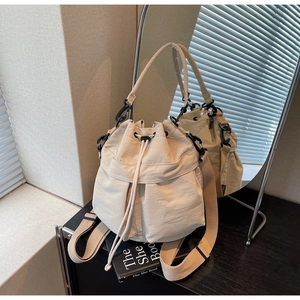 Beige drawstring bucket bag in nylon with hand strap and long crossbody shoulder strap