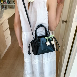 Detail of black patent leather bucket bag with TonTon embossing and floral charm detail