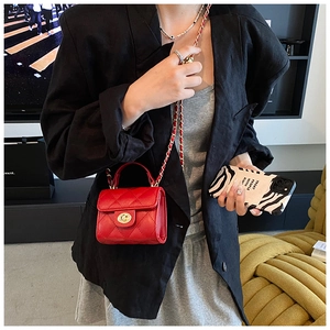 Detail of red quilted mini chain bag with gold twist lock on a modern fashion model