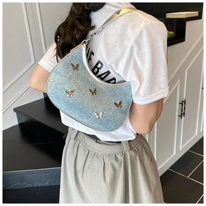 Dettaglio borsa hobo in denim azzurro con farfalle metalliche e tracolla argento lucido