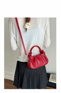 Detail of red pleated cloud bag with silver hardware and detachable crossbody strap