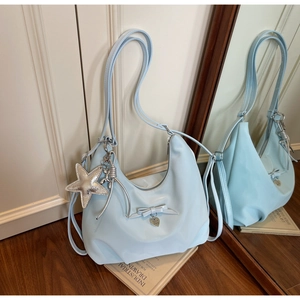 Detail of baby blue satin bag with bow decoration and trendy metallic star charms
