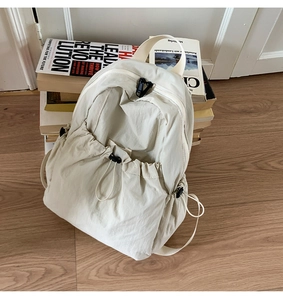Detail of beige nylon drawstring backpack with pleated texture and black buckles