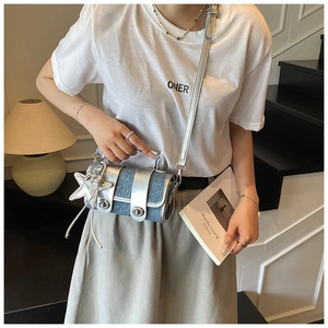 Gros plan du mini sac en jean bleu avec garniture argentée et pendentif étoile porté