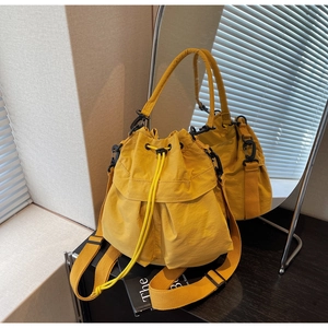 Detail of a bright yellow nylon bucket bag with a drawstring closure and a wide strap