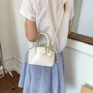 Detail of cream mini bucket bag with Ton Ton embossing and tulip flower charm accessory