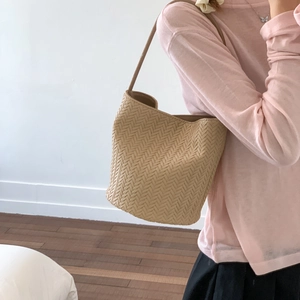 Detailed close-up of light beige woven bucket bag showing premium texture and shoulder strap