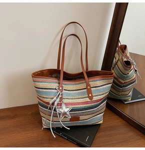 Detail of colorful striped woven tote bag with brown leather straps and star charm