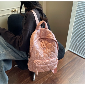 Detailed view of pink quilted heart backpack with adjustable straps worn by a model