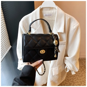 Detailed close-up of black quilted leather handbag with gold twist lock and metal chain strap