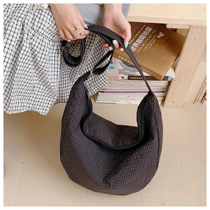 Detail einer schwarz-weiß karierten Hobo-Schultertasche, gehalten in einem Zimmer