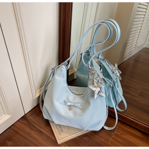 Detail of light blue hobo bag with star charm and bow on industrial design book
