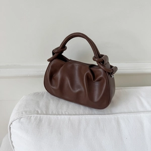 Detail of dark brown leather cloud bag with pleated texture and stylish knotted handle