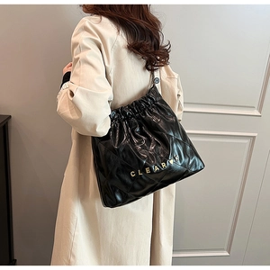 Detail view of black quilted leather bucket bag with metal chain strap and logo