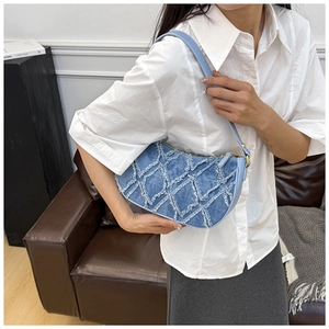 Detail of sky blue denim baguette bag with quilted frayed edges and golden hardware
