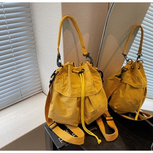 Detail view of the bright yellow water-resistant nylon bucket bag with black metal hardware