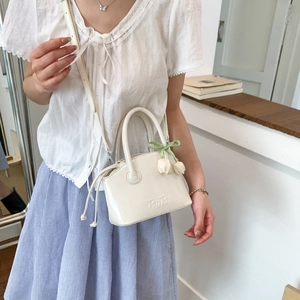 Detail of cream mini bucket bag with Tonton embossed logo and tulip flower charm