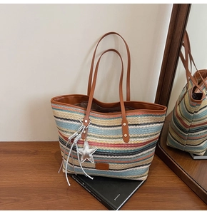 Detail of colorful rainbow woven tote bag with brown leather straps and star charm