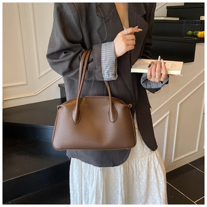 Borsa tote in pelle marrone con trama litchi ed eleganti manici sottili tenuti da una modella