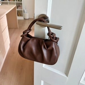 Detail of dark brown ruched cloud bag showing premium pleated leather and knot handle