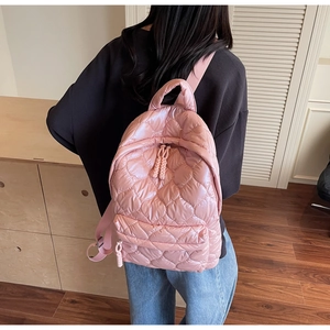 Detail of pink puffer backpack featuring heart quilted patterns and woven zipper pulls