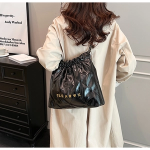 Detail of black quilted leather drawstring bag with gold metal letters on a model