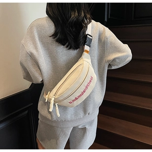 Détail du sac de poitrine en toile beige avec broderie rose et sangle ajustable