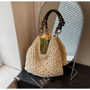 Detail of hand-woven straw tote with vintage dark brown wooden bead handles on a desk