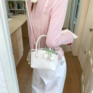 Detail of white mini bucket bag with TonTon logo and tulip charm on a female model