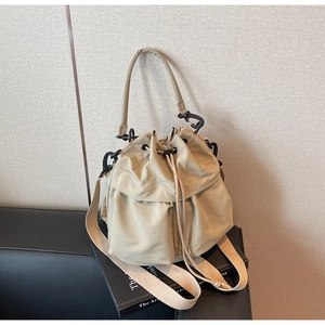 Detail of khaki drawstring bucket bag with black matte hardware and wide crossbody strap