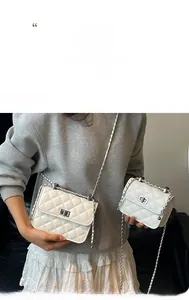 Detail of white quilted crossbody bag featuring silver metal twist lock and chain strap