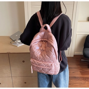 Pink quilted heart-pattern backpack shown on a model in a cozy home office setting